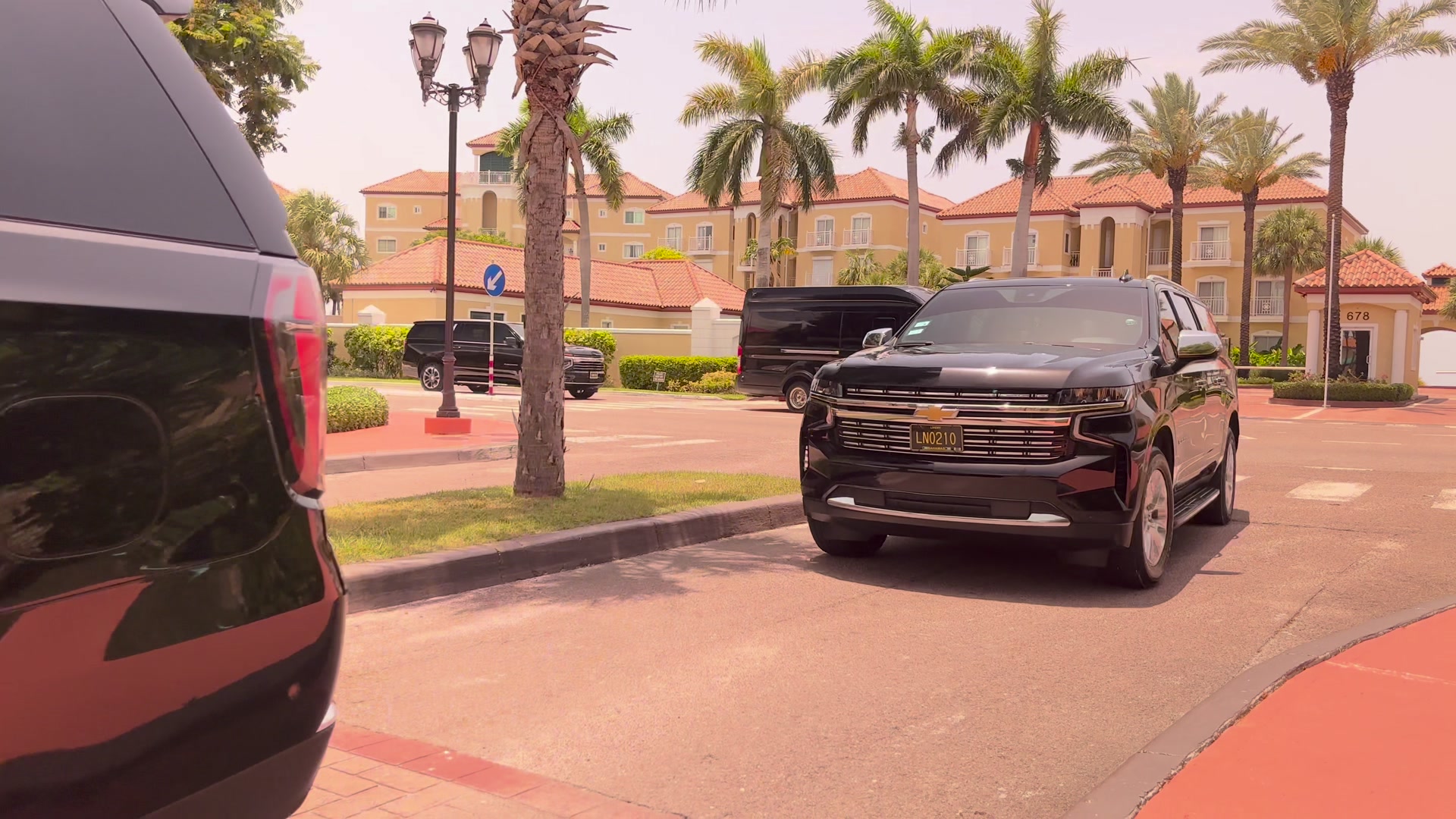A black Chevrolet Suburban pulling up to a resort entrance lined with palm trees in Nassau